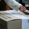Persona depositando su voto en una urna.