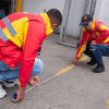 Imagen de dos personas midiendo con un metro el piso de un parqueadero