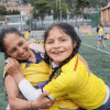 Imagen de una madre junto a su hija quien la abraza y sonríe