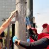 Funcionarios del DADEP limpiando un poste de luz de publicidad no permitida.