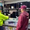 Policía y funcionario del Distrito inspeccionando establecimiento comercial dedicado a la compra y venta de equipos tecnológicos.