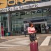 Foto de una mujer con su maleta de viaje frente al Aeropuerto Internacional El Dorado de Bogotá.