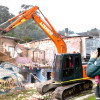 Foto que muestra una retroexcavadora tumbando una casa 