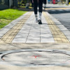 Foto que muestra una persona caminando por un andén en el que se ve una tapa de alcantarillado