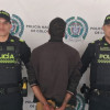 Hombre capturado, de espaldas, en medio de dos policías.