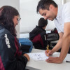 Foto que muestra dos personas hablando y escribiendo en un papel 