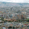 Panorámica de Bogotá con amplia zona urbana, edificaciones densas y cerros al fondo bajo cielo nublado