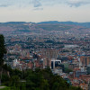 Panorámica de Bogotá con edificios, cerros orientales y cielo parcialmente nublado