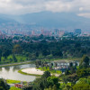 Vista panorámica de Bogotá, lago, senderos y arbolados de la ciudad con vista a montañas y cielo nublado