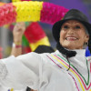 Persona mayor participa en actividad cultural con vestuario tradicional y accesorios coloridos durante presentación recreativa