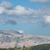 Panorámica de Bogotá con cerros poblados y cielo parcialmente nublado al fondo