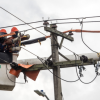 Imagen de dos técnicos de ENEL realizando trabajos de mantenimiento en un poste de energía.