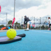 Raqueta de pickleball y una bola verde en un cancha para practicar este deporte
