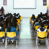 Foto que muestra estudiantes de colegio sentados en un auditorio