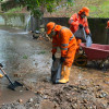Foto que muestra tres personas con el uniforme de Aguas de Bogotá limpiando un canal