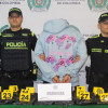 El hombre de la pareja, detenido en medio de dos policías, con el cargamento de marihuana sobre una mesa.