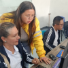 Imagen de una funcionaria ayudándole a una señora en un computador
