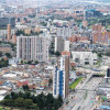 Vista aérea de Bogotá con edificaciones, avenidas principales y zonas verdes en día nublado.