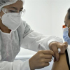 Imagen de una enfermera aplicando una vacuna a una mujer de mediana edad que usa tapabocas