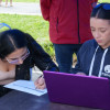 Foto que muestra dos mujeres sentadas escribiendo en un papel sobre una mesa