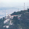 Vista del Santuario de Monserrate en cerro boscoso con ciudad de Bogotá al fondo