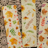 Imagen de una mesa en la que hay unas pinturas, un picnel y tres servilletas con dibujos de flores.