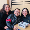 Imagen de tres personas sosteniendo dos cajas