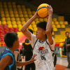 Jóvenes disputan partido de baloncesto en escenario deportivo cubierto de Bogotá.