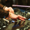Imagen de consola de música eléctronica con manos de mujer tocando discos