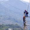 Imagen que muestra dos técnicos de Enel realizando mantenimiento a un poste de luz, de fondo se ve la ciudad.