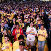 Multitud numerosa reunida en fanzone del Parque El Tunal observa partido de la Selección Colombia en pantallas gigantes; asistentes visten camisetas amarillas, sostienen banderas, teléfonos móviles y aplauden de pie en jornada nocturna.