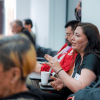 Mujer en el público de un evento o charla, hablando.