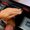 Manos de una mujer retirando plata en un cajero automático.