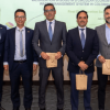 Foto que muestra cinco hombres en un auditorio sonriendo 