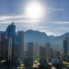 Vista panorámica de Bogotá con edificios modernos, cerros orientales y sol alto sobre cielo despejado