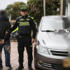 Dos policías con hombre capturado y vehículo recuperado.