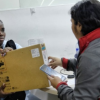 Imagen de una funcionaria entregando un computador a una mujer
