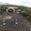Vista aérea de concierto masivo en el parque Simón Bolívar con miles de asistentes reunidos frente a un escenario principal rodeado de zonas verdes y árboles.