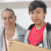 Imagen de Yasmín sonriendo junto a su hijo quien carga el computador