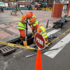 Foto que muestra dos personas con uniforme de Aguas Bogotá limpiando un sumidero