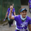 Imagen de referencia sobre participante de la carrera Sube Monserrate avanza por el sendero empedrado, viste camiseta morada con el texto “Sube Monserrate” y lleva el número de competencia sujeto a la cintura.