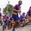 Imagen de referencia sobre participantes de la carrera Sube Monserrate ascienden al inicio del recorrido, vistiendo camisetas moradas del evento y números de competencia visibles en el pecho.
