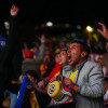 Multitud reunida en fanzone nocturno de Bogotá observa partido en pantallas gigantes, con asistentes levantando brazos, vistiendo prendas de la Selección Colombia