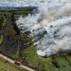 Vista aérea del humedal Jaboque durante un incendio de cobertura vegetal, con extensas columnas de humo, áreas afectadas por el fuego, vehículos de emergencia y edificaciones cercanas.