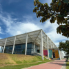 Foto que muestra un edificio con techo blanco y paredes en cristal 