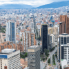 Vista panorámica de Bogotá con torres residenciales y empresariales, corredores viales, alta concentración de edificaciones y cerros orientales al fondo.