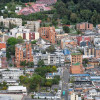 Vista aérea de Bogotá con edificaciones residenciales y cadena montañosa verde al fondo