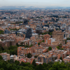 Vista panorámica de Bogotá con alta concentración de edificios residenciales y comerciales, amplias zonas arboladas en primer plano y expansión urbana que se extiende hacia el occidente de la ciudad.
