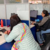 Foto que muestra tres personas sentadas frente a modulos de atención 