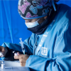 Imagen de una mujer vestida con chaqueta azul de la Secretaría de Salud preparando una geringa para vacunar.